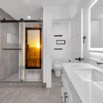 White and grey bathroom. Standing shower has a door leading outside to an upstairs balcony.