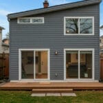 Two story disconnected ADU with a slanted roof and wood patio deck.