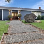 Large boulder on lawn in front of house.