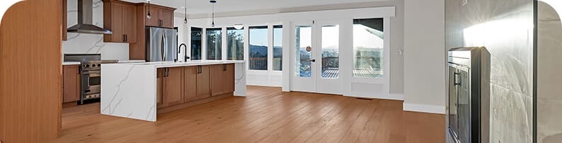 A large, open kitchen space with brown wood floors, white and grey walls, and marble countertops.